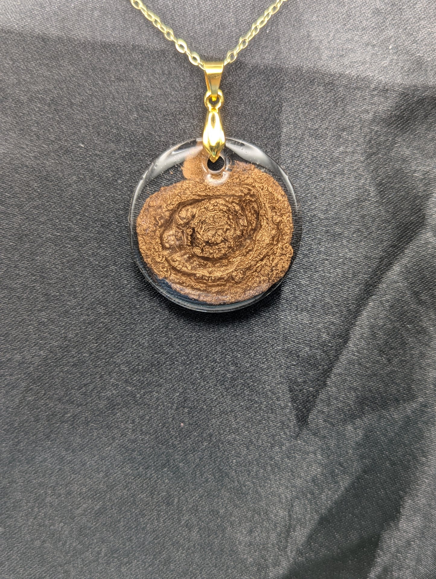 Gold Swirl Resin Circle pendant on a gold pinch bail and gold plated metal chain.