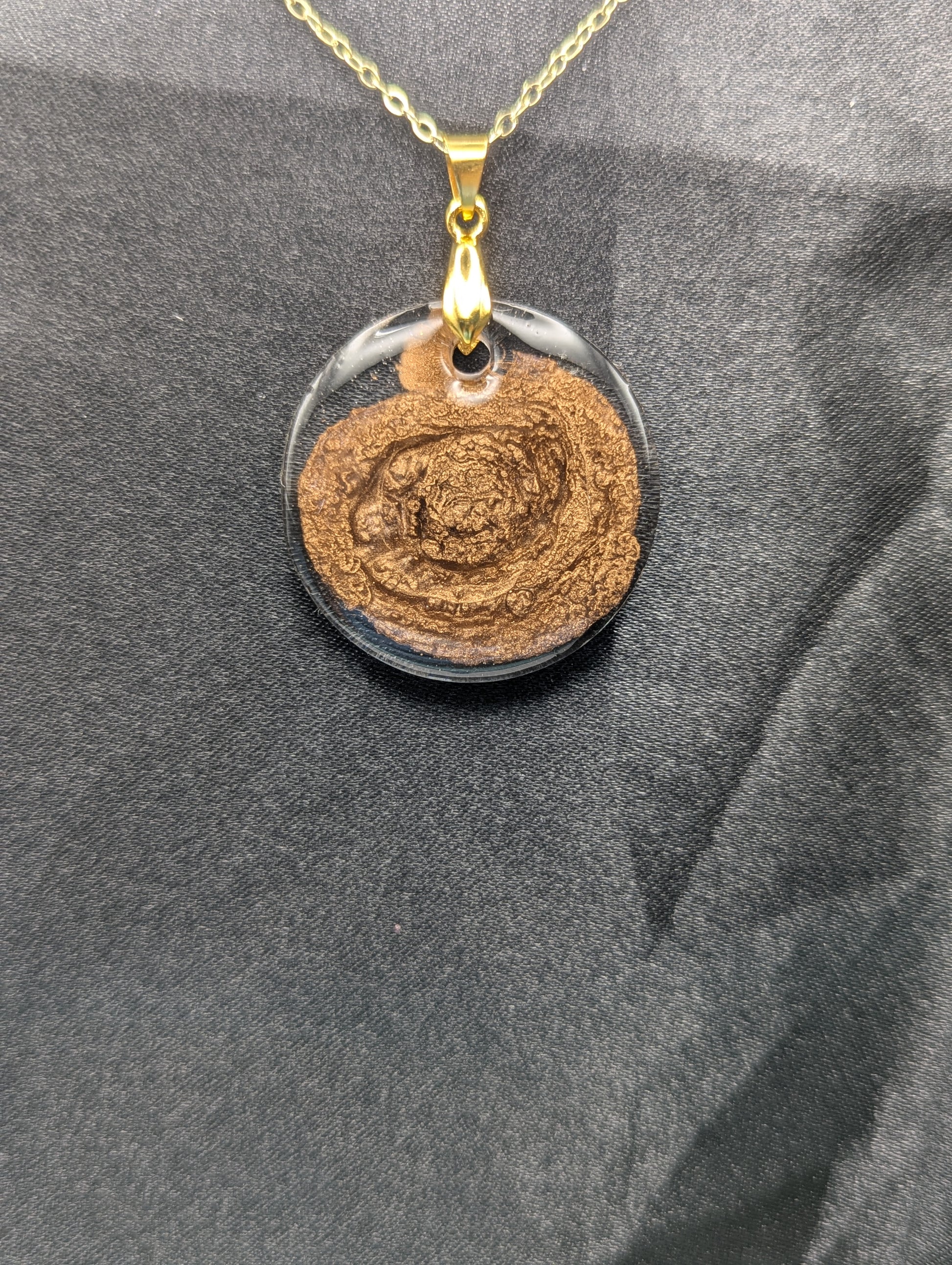 Gold Swirl Resin Circle pendant on a gold pinch bail and gold plated metal chain.