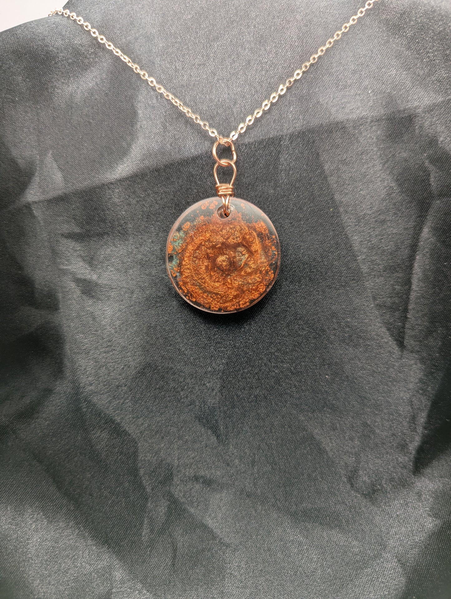 Back view of Copper swirl resin circle pendant, wrapped in a pure copper wire on a rose gold colored stainless steel plated metal chain.