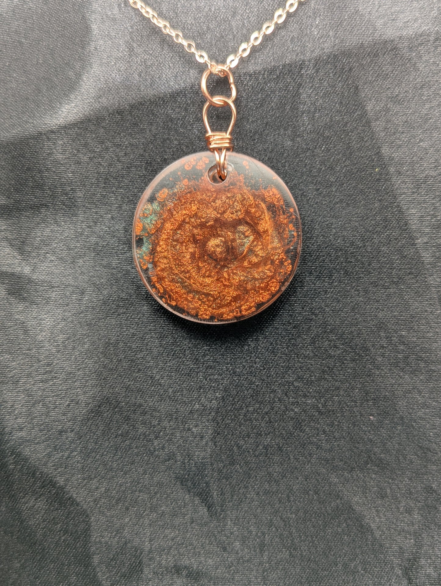 Back view of Copper swirl resin circle pendant, wrapped in a pure copper wire on a rose gold colored stainless steel plated metal chain.