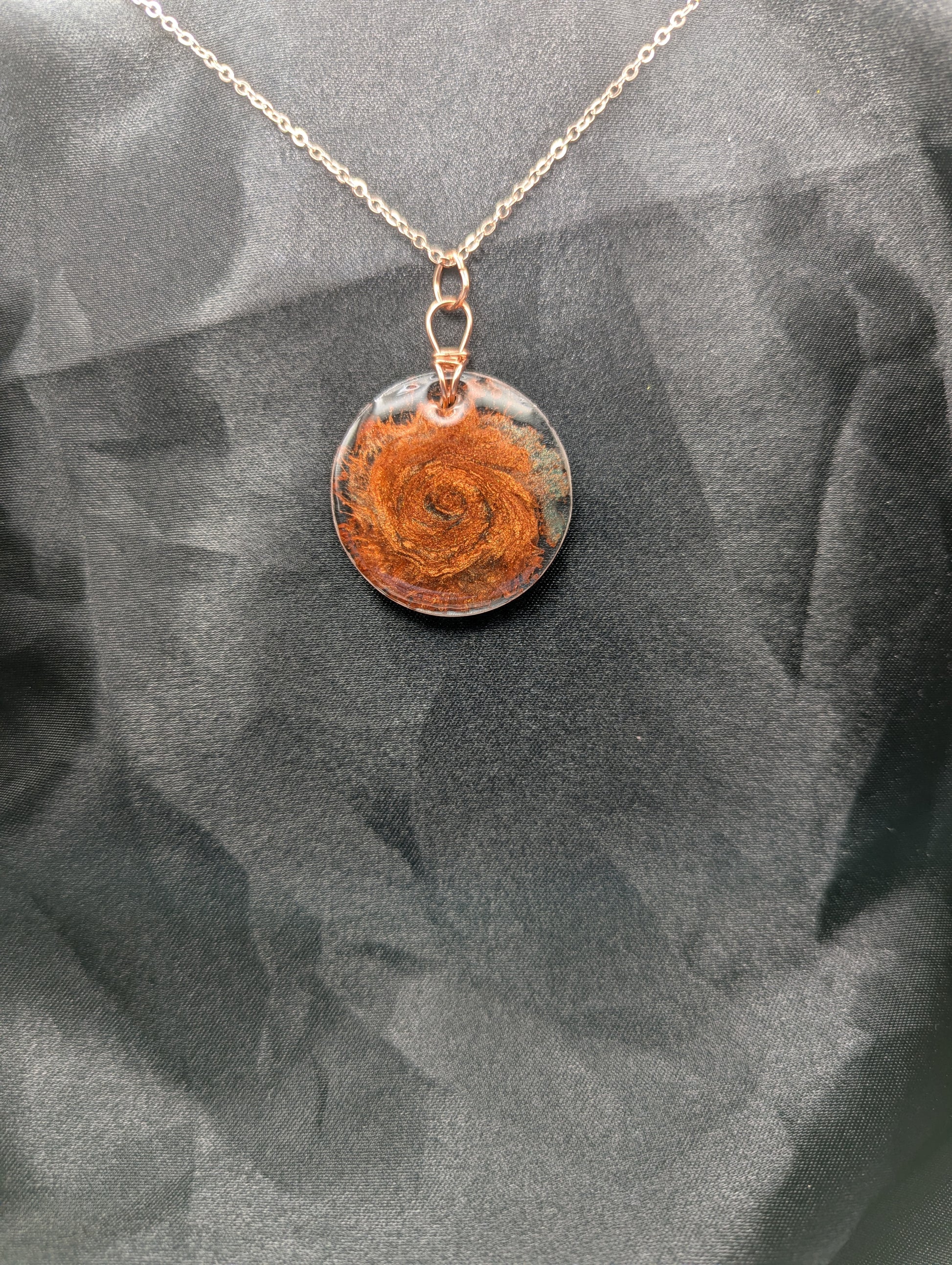 Copper swirl resin circle pendant, wrapped in a pure copper wire on a rose gold colored stainless steel plated metal chain.