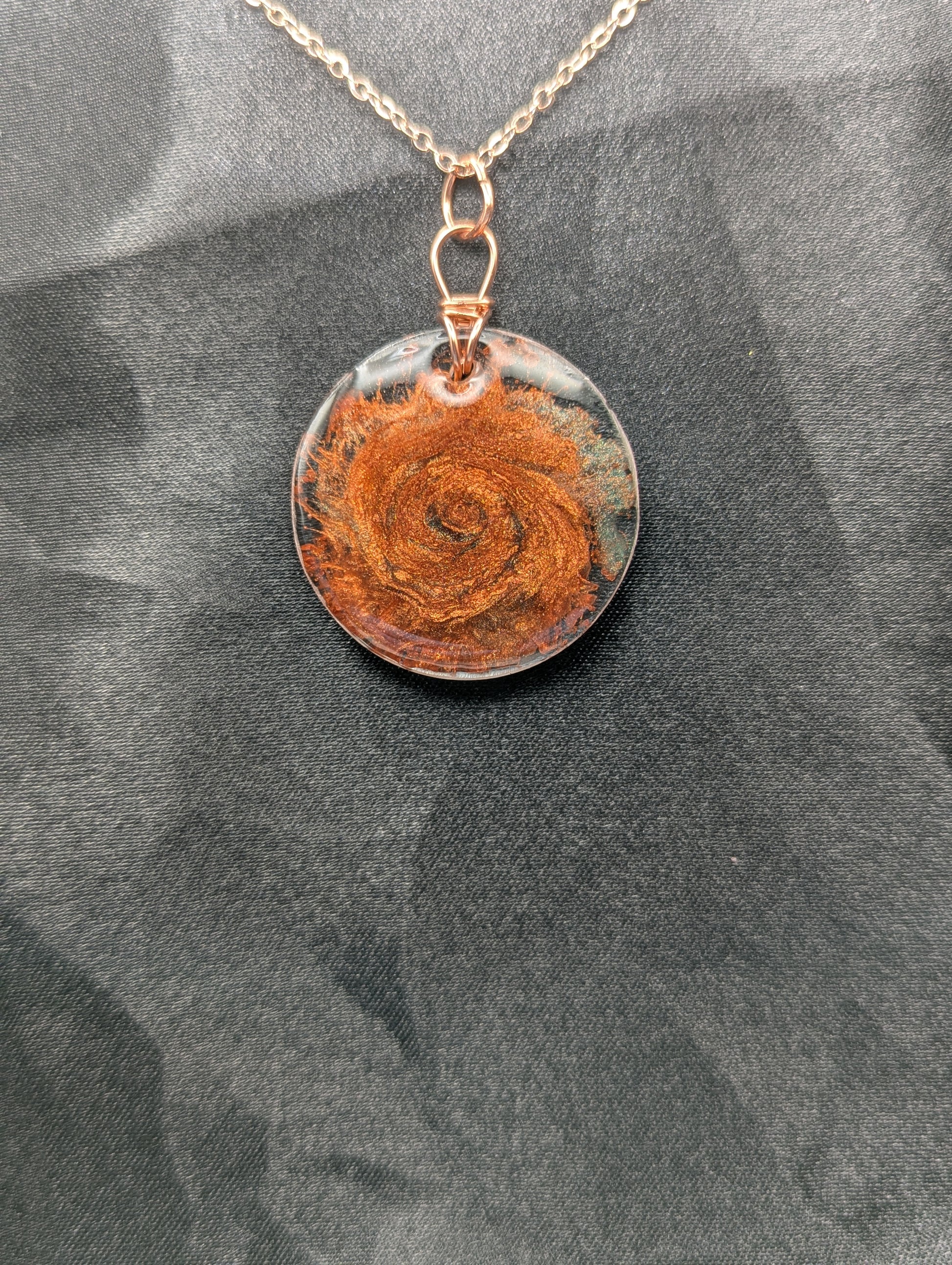 Copper swirl resin circle pendant, wrapped in a pure copper wire on a rose gold colored stainless steel plated metal chain.