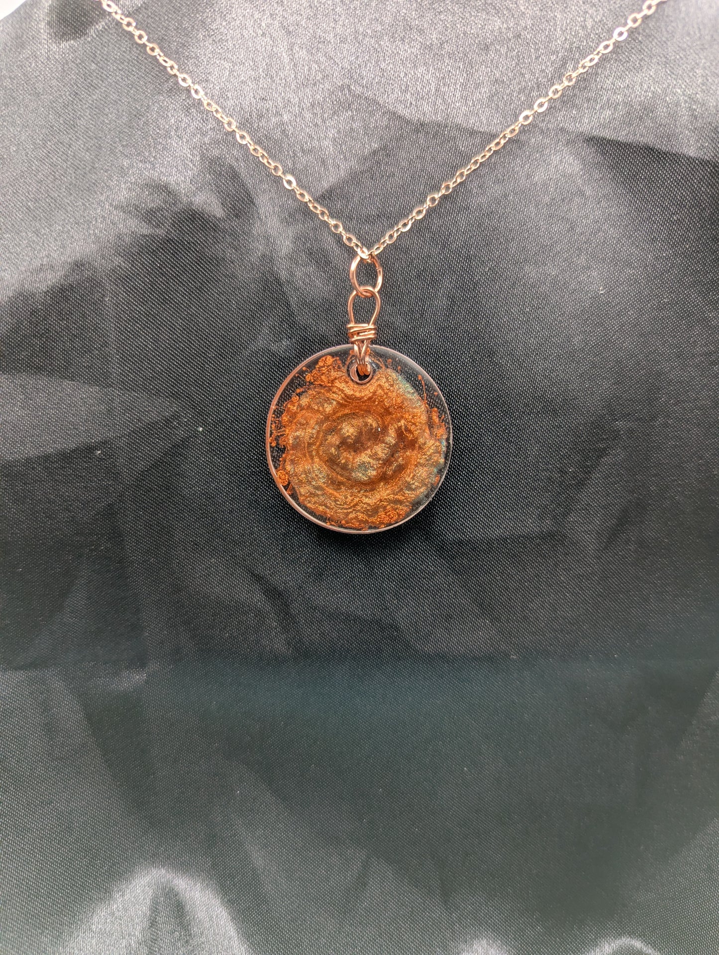 Back view of Copper Swirl Circle Resin Pendant wrapped in a pure copper wire on a rose colored stainless steel plated metal chain.