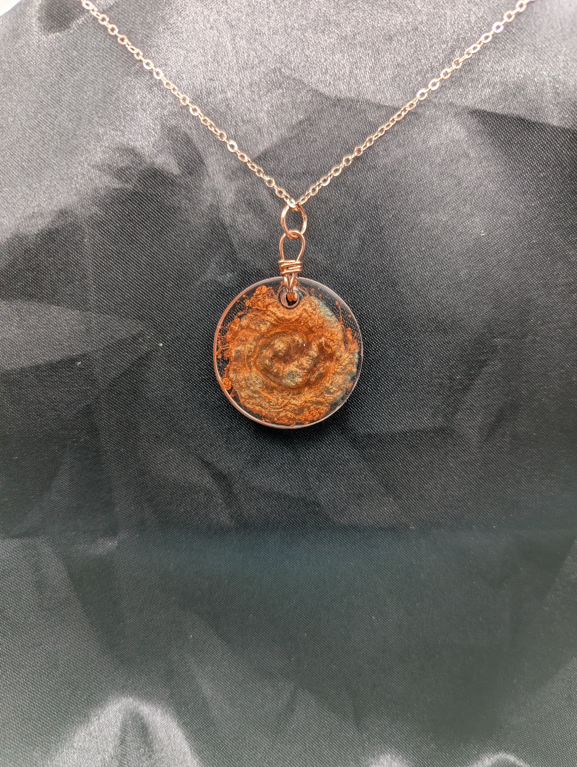 Back view of Copper Swirl Circle Resin Pendant wrapped in a pure copper wire on a rose colored stainless steel plated metal chain.