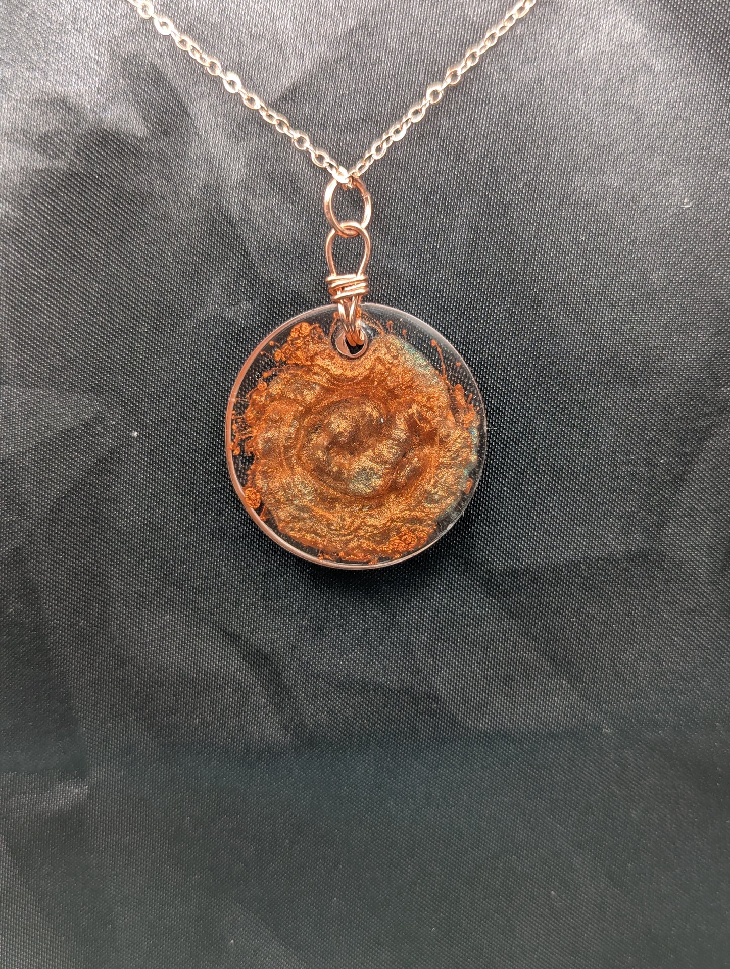 Back view of Copper Swirl Circle Resin Pendant wrapped in a pure copper wire on a rose colored stainless steel plated metal chain.