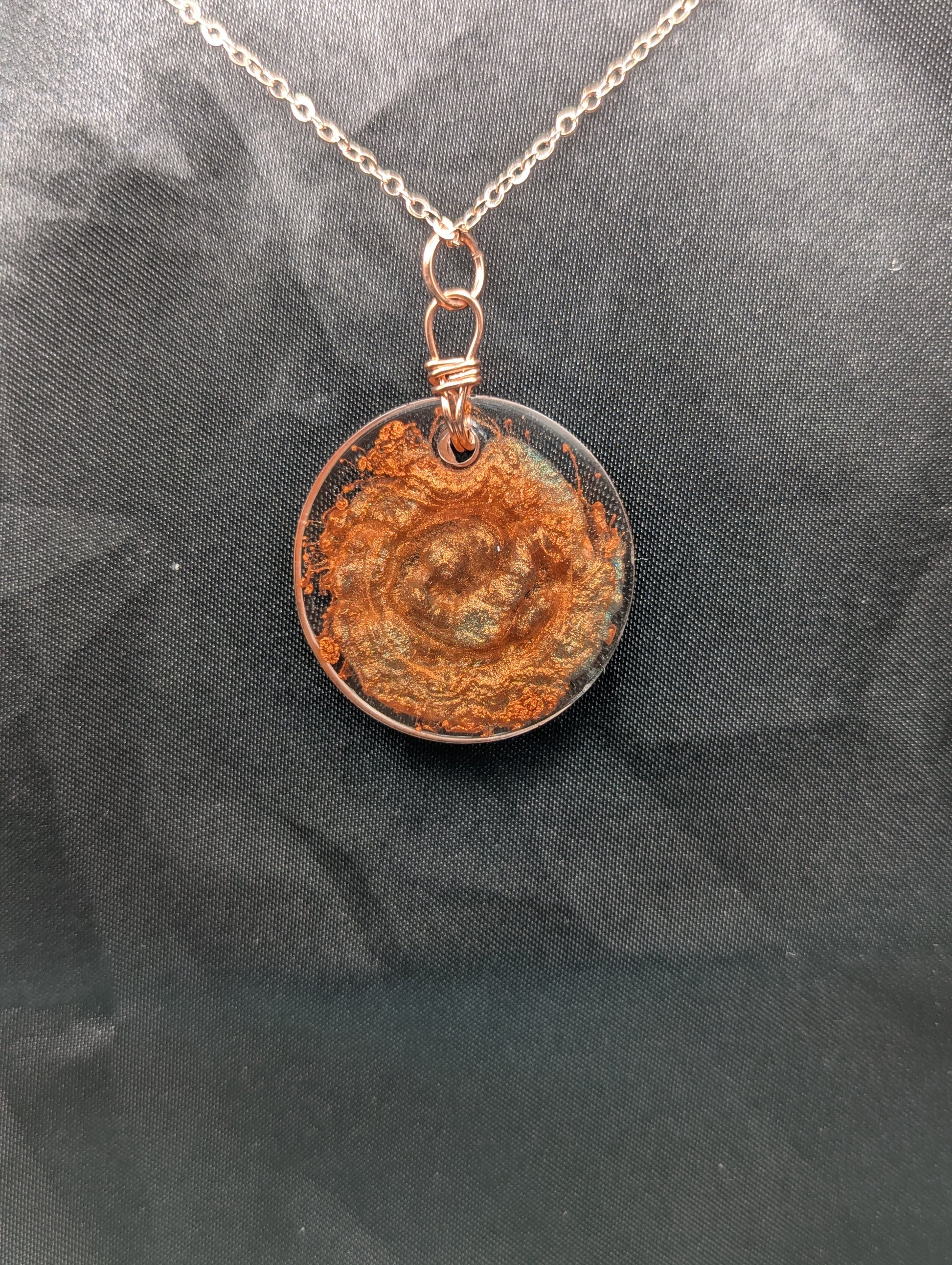 Back view of Copper Swirl Circle Resin Pendant wrapped in a pure copper wire on a rose colored stainless steel plated metal chain.
