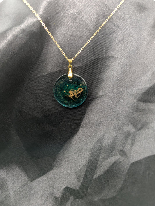 Emerald green circle resin pendant swirled with gold pigment on a gold pinch bail with a gold plated metal chain.