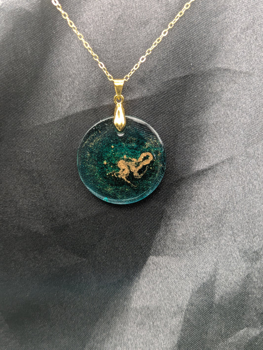 Emerald green circle resin pendant swirled with gold pigment on a gold pinch bail with a gold plated metal chain.