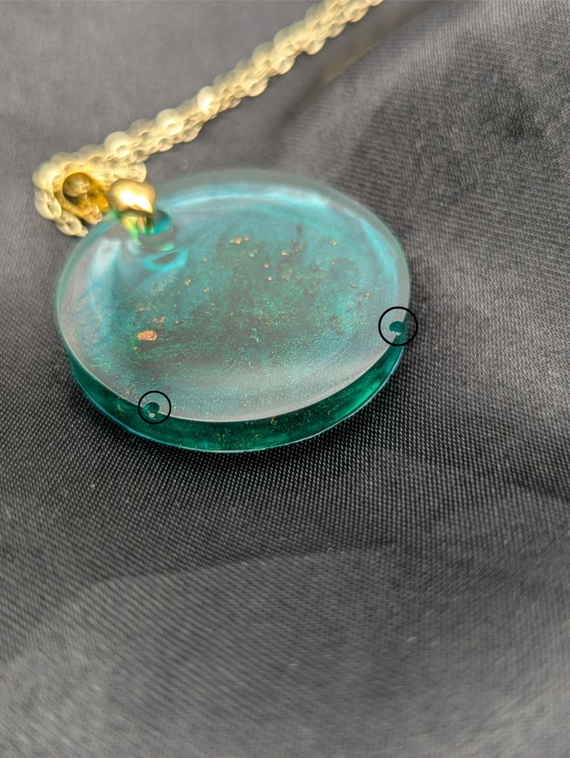 Emerald green circle resin pendant swirled with gold pigment on a gold pinch bail with a gold plated metal chain.