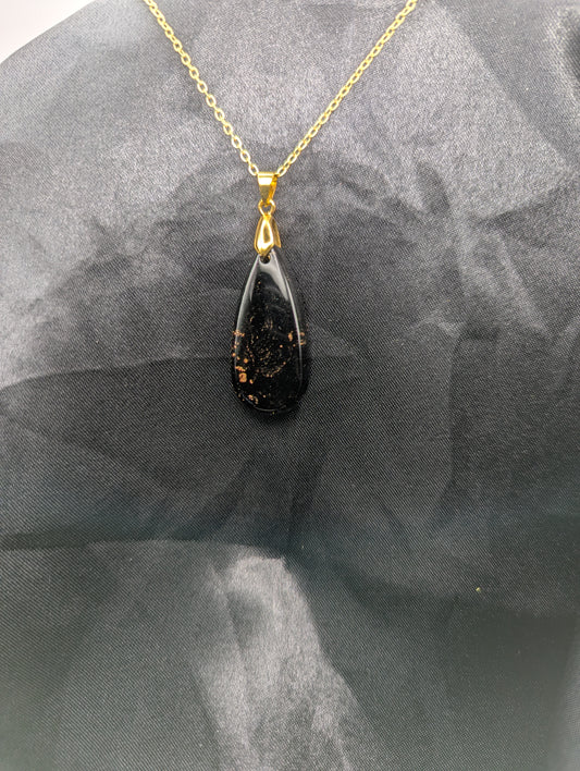 Black Resin Teardrop Pendant with specks of sparkly gold swirled inside. Pendant is on a gold pinch bail & gold plated metal chain.