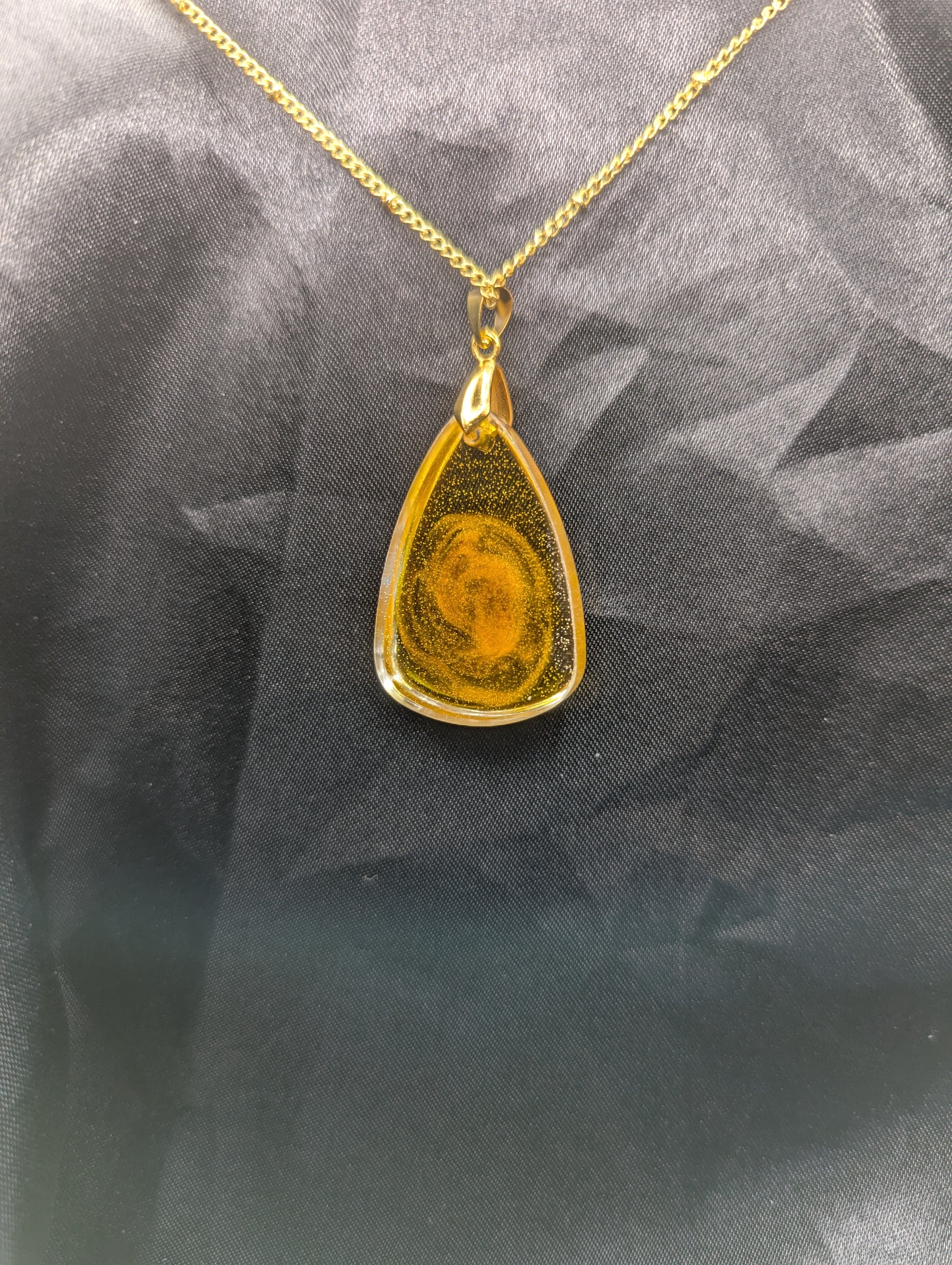 Back view of Yellow & Orange Swirl Rounded Triangle Resin Pendant Necklace on a gold pinch bail and a gold plated metal chain.