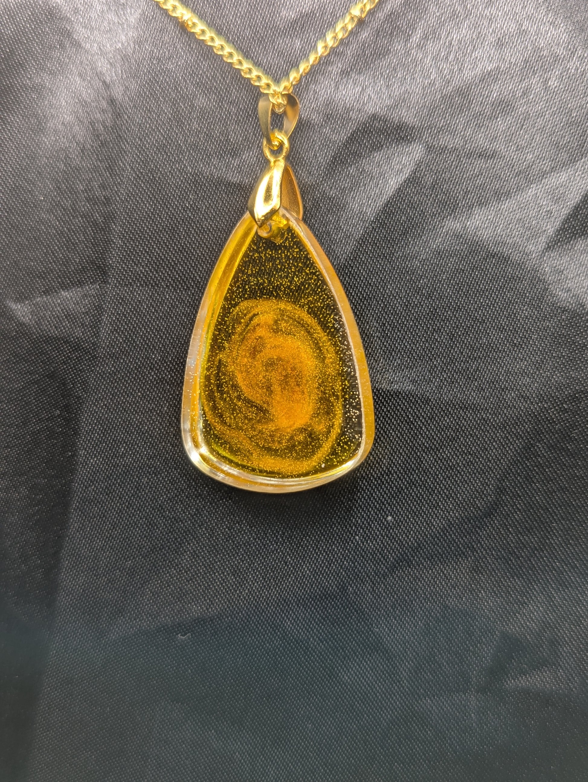 Back view of Yellow & Orange Swirl Rounded Triangle Resin Pendant Necklace on a gold pinch bail and a gold plated metal chain.