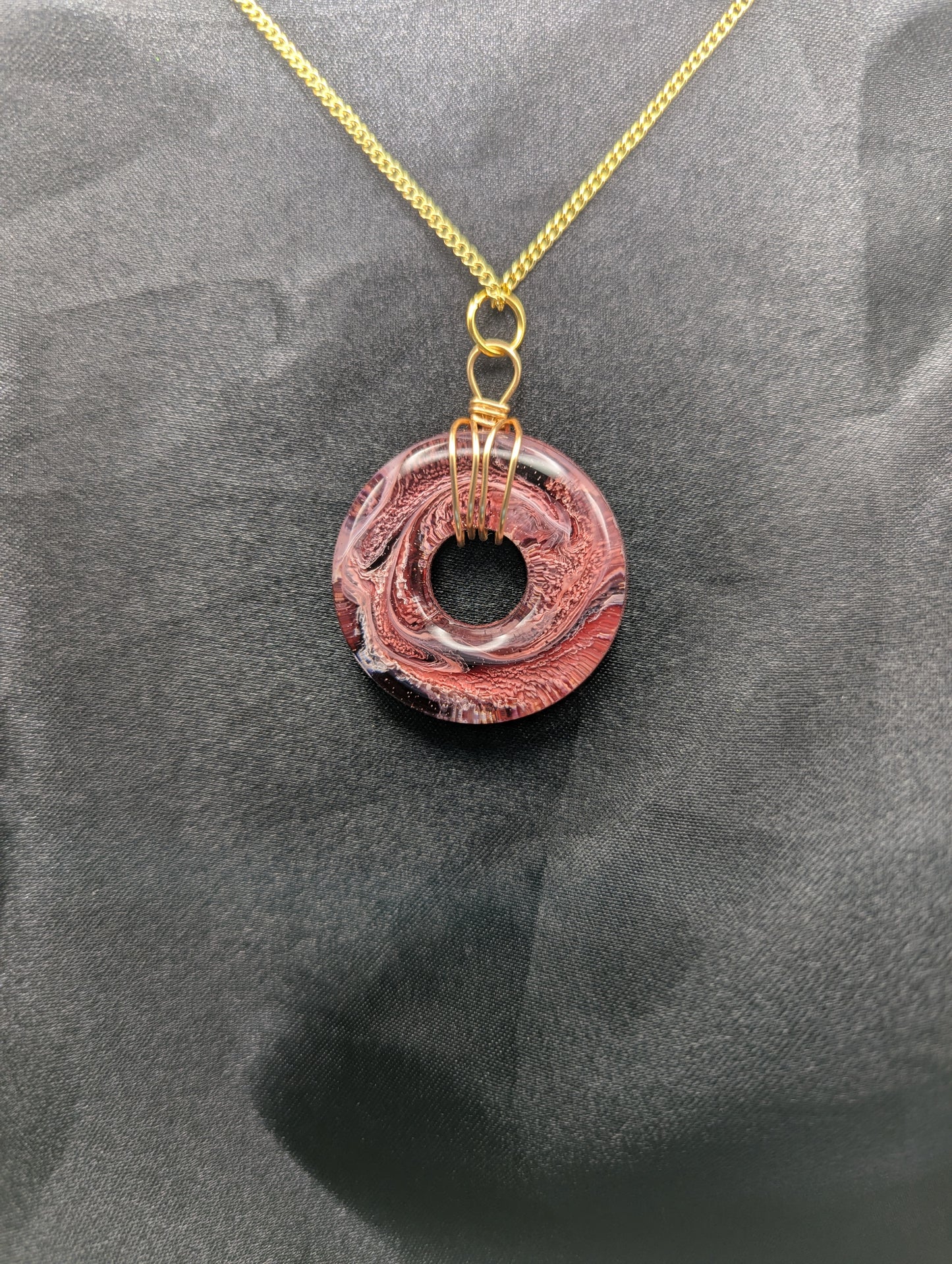Wire Wrapped Donut Resin Pendant Necklace - Petri Effect with shades of red & black swirls. Resin Necklace on a gold plated metal chain.