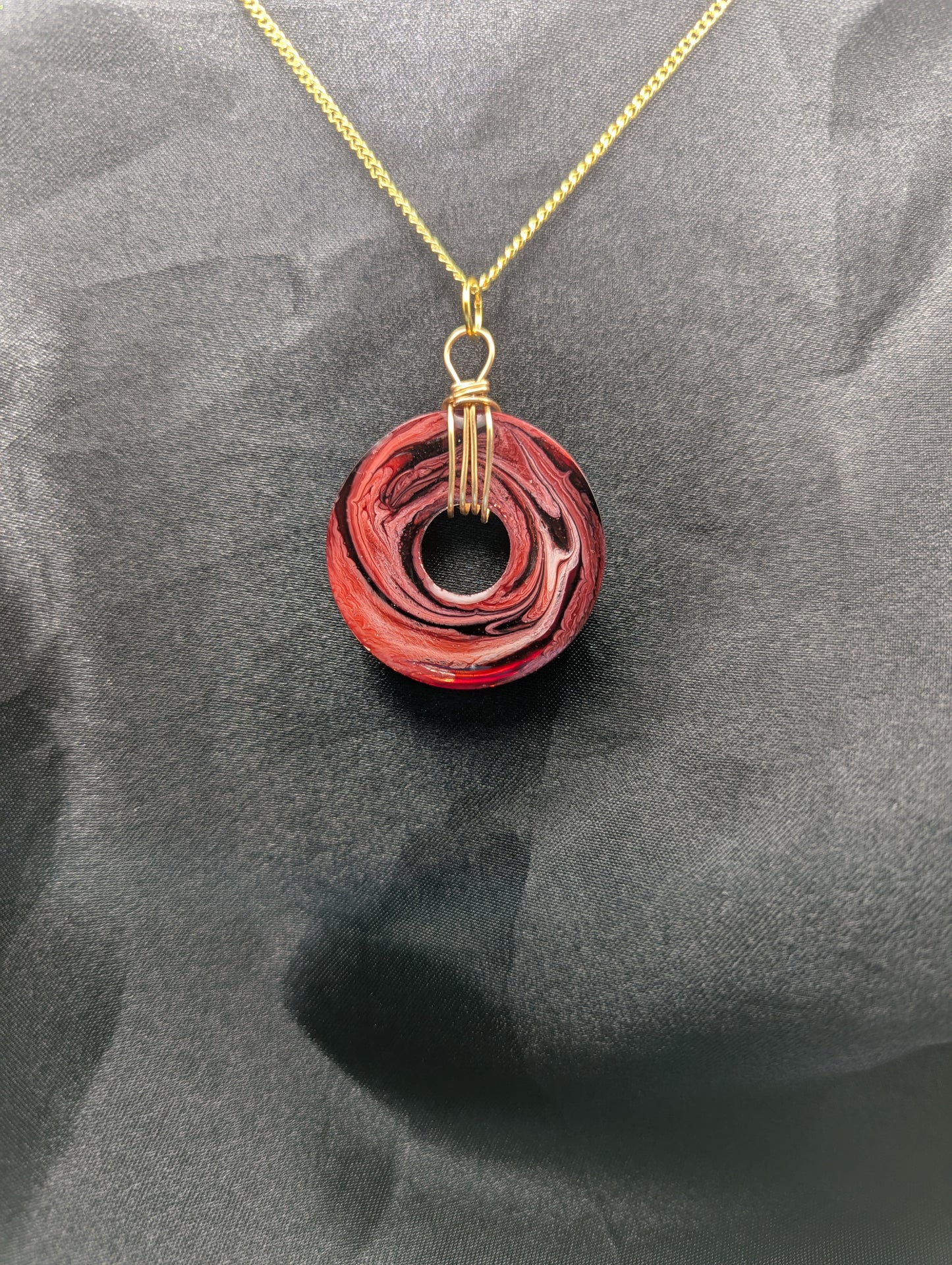 Back view of Wire Wrapped Donut Resin Pendant Necklace - Petri Effect with shades of red & black swirls. Resin Necklace on a gold plated metal chain.