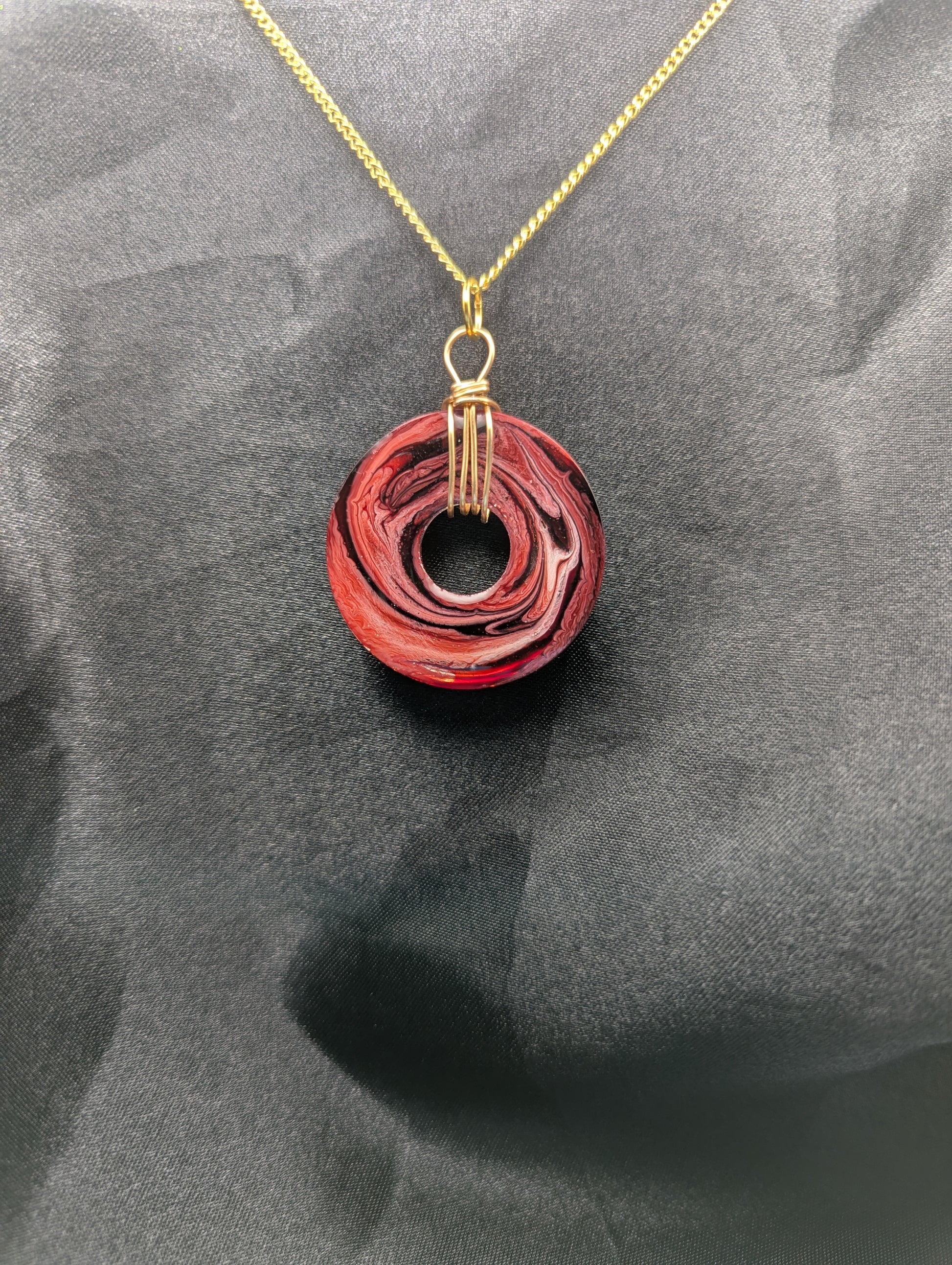 Back view of Wire Wrapped Donut Resin Pendant Necklace - Petri Effect with shades of red & black swirls. Resin Necklace on a gold plated metal chain.