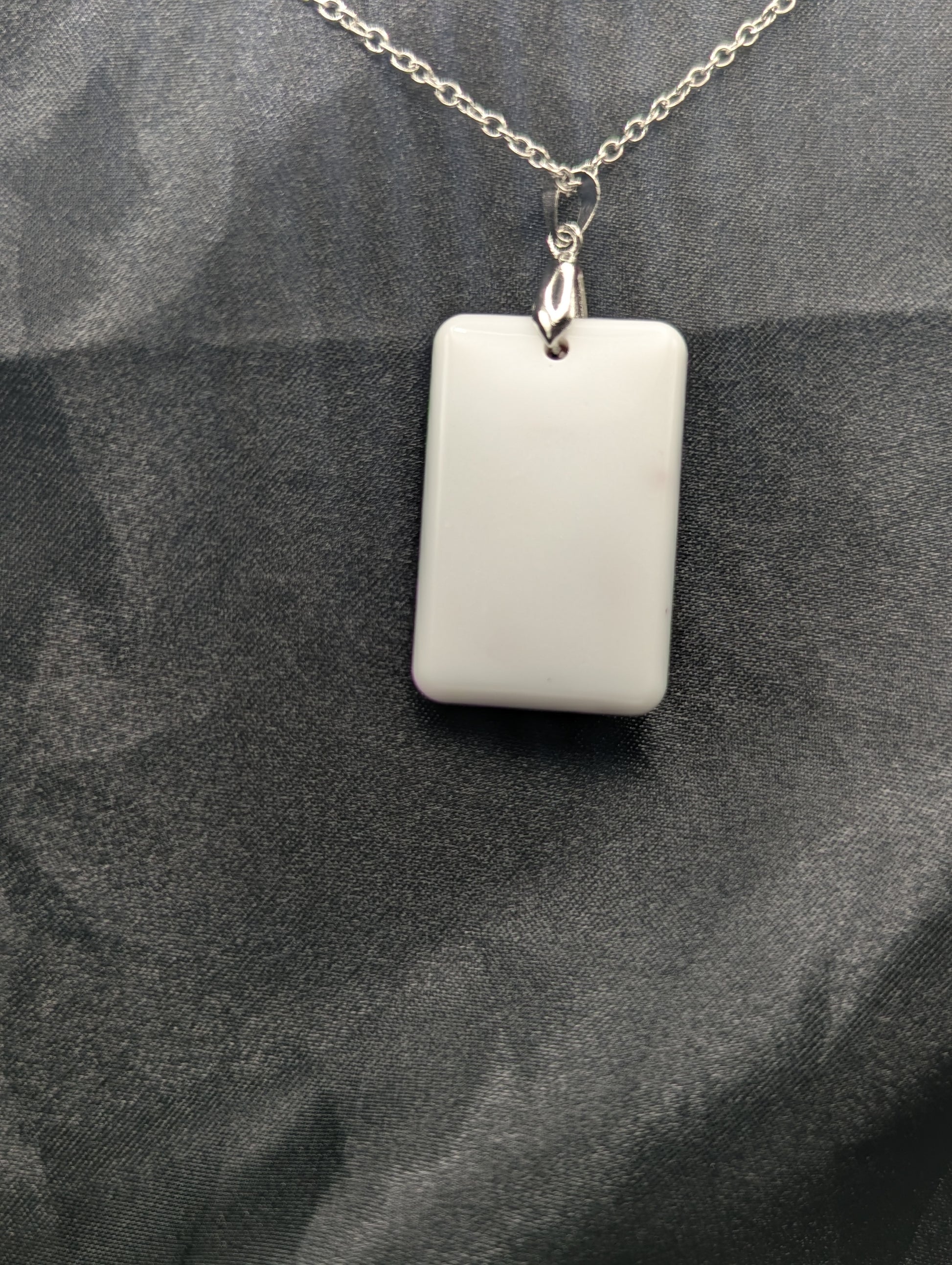 Back view of Rectangle resin pendant necklace with dark red swirls and a white background. Resin necklace on a silver pinch bail & stainless steel chain.