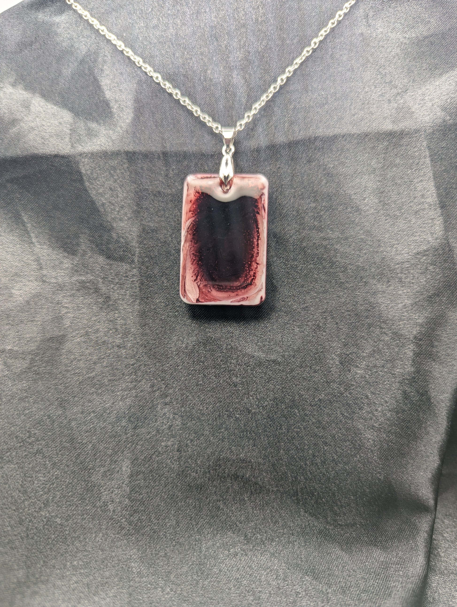 Rectangle resin pendant necklace with dark red swirls and a white background. Resin necklace on a silver pinch bail & stainless steel chain.