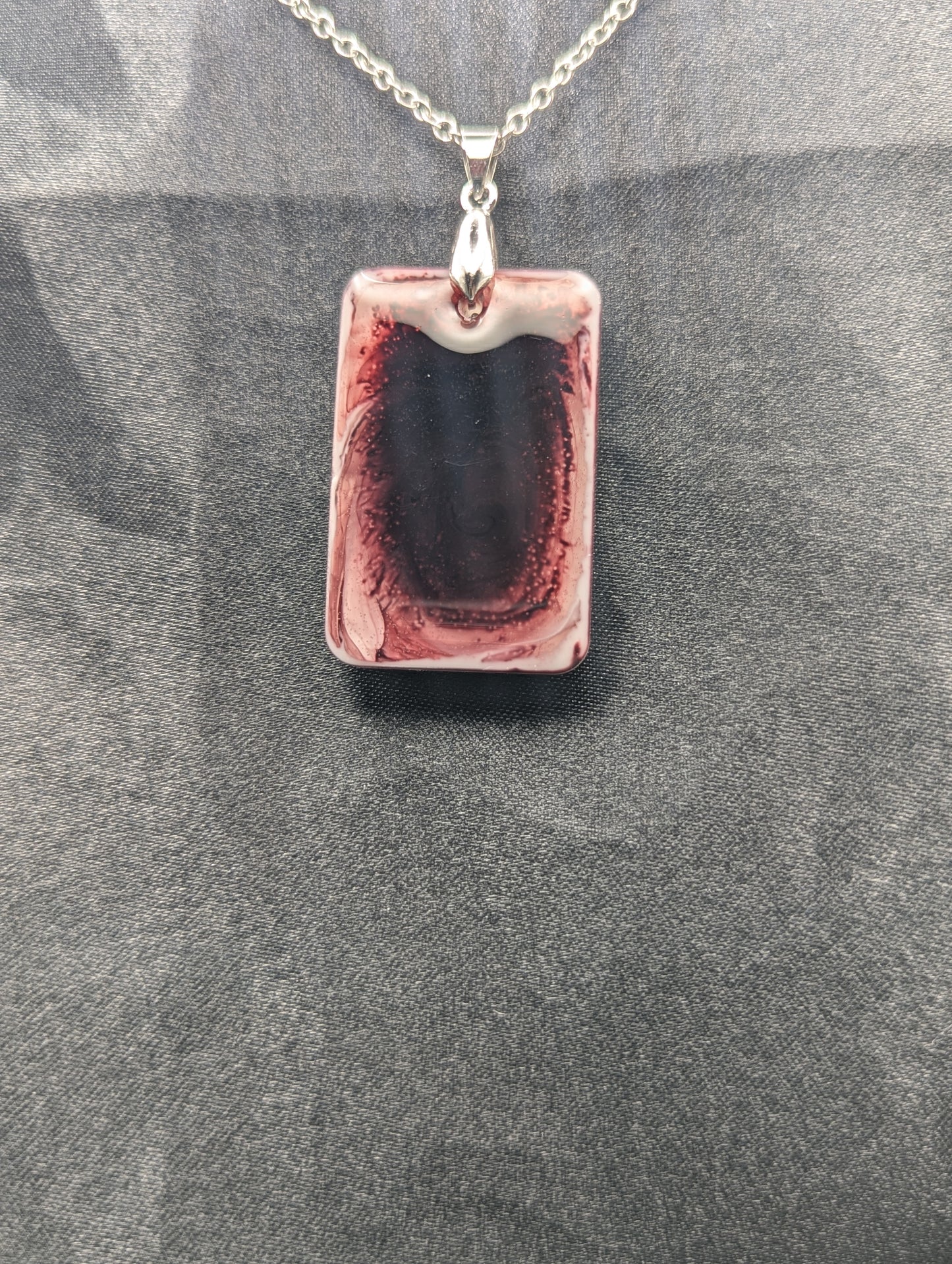 Rectangle resin pendant necklace with dark red swirls and a white background. Resin necklace on a silver pinch bail & stainless steel chain.