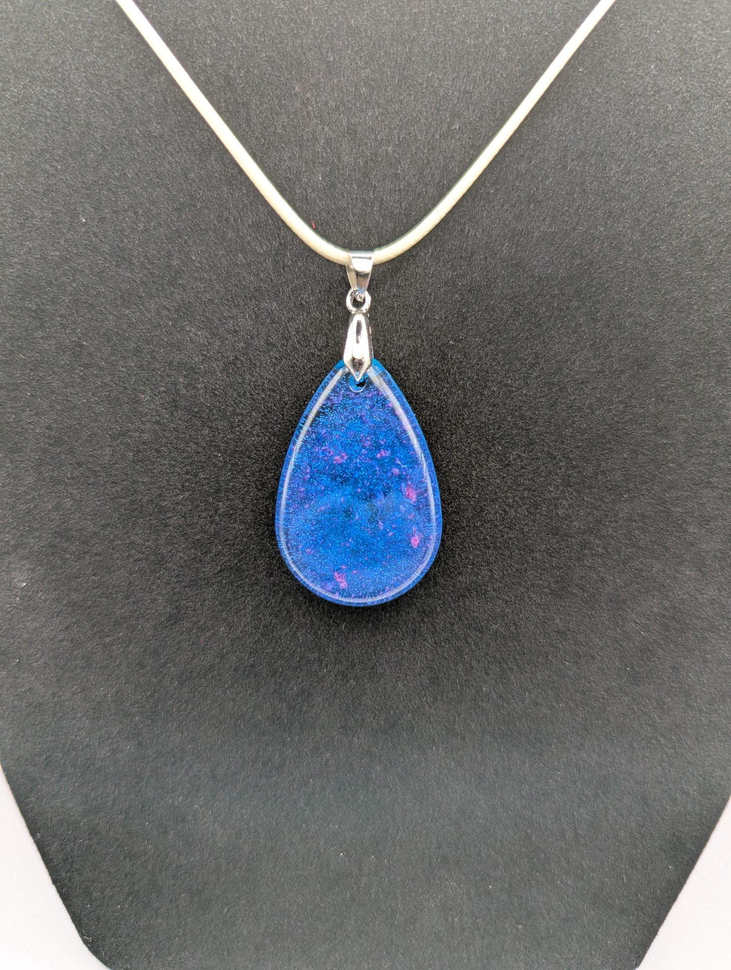 Teardrop Resin Pendant Necklace - Blue & sparkly in color with pops of bright purple. Resin necklace on a waxed cotton cord.