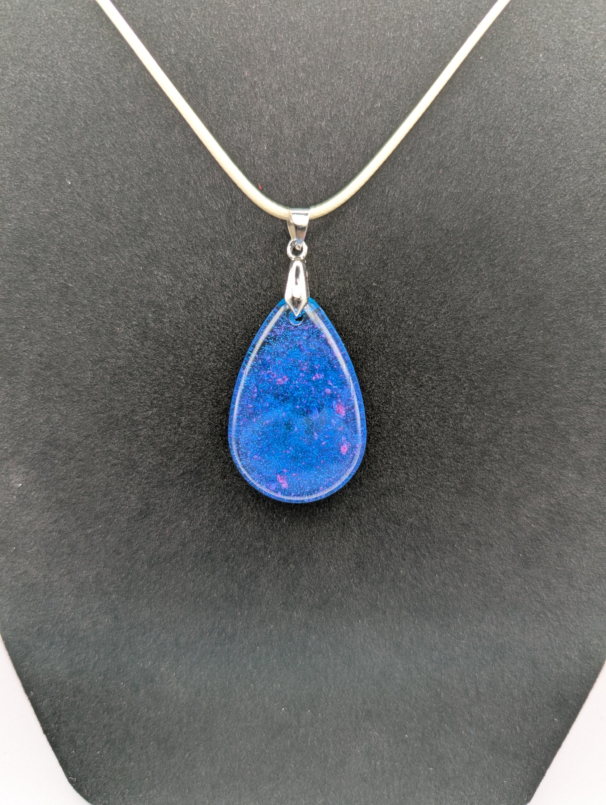 Teardrop Resin Pendant Necklace - Blue & sparkly in color with pops of bright purple. Resin necklace on a waxed cotton cord.