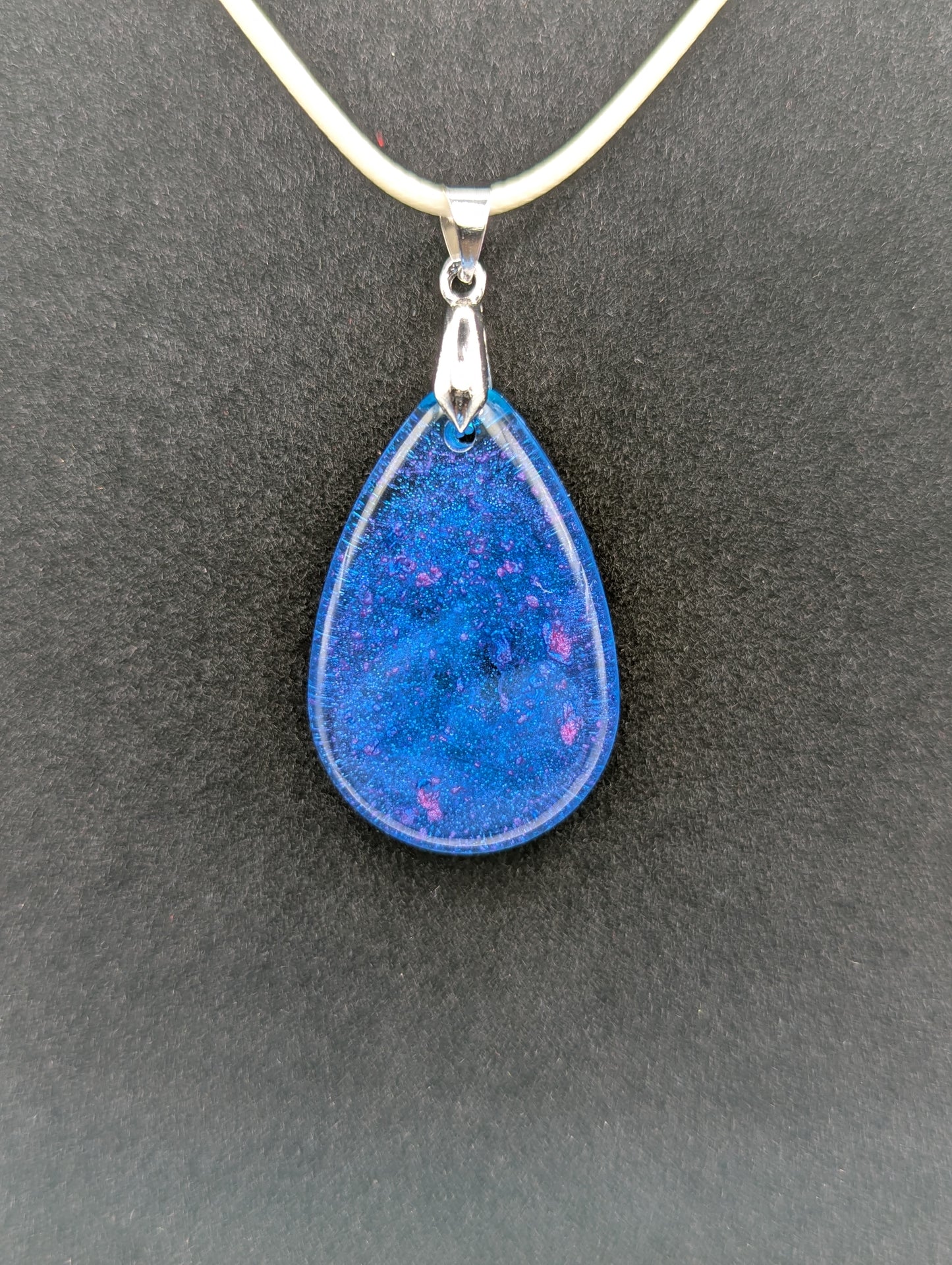 Teardrop Resin Pendant Necklace - Blue & sparkly in color with pops of bright purple. Resin necklace on a waxed cotton cord.
