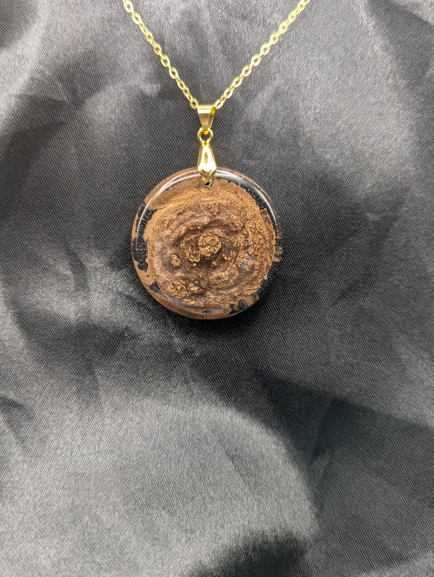 Rich Gold Swirl Resin Circle Pendant on a gold pinch bail and gold plated metal chain.