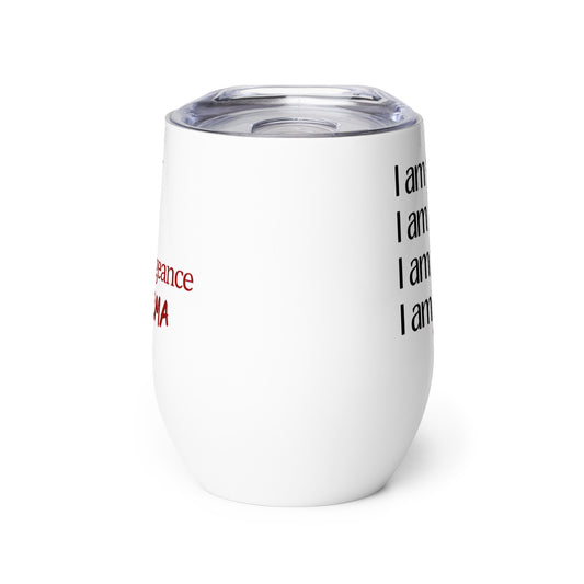 An insulated stemless wine glass with a lid for drinking wine in a tumbler. Cup is white in color with the words "I am spite, I am rage, I am vengeance, I am karma" on it. Each "I am" is in black font & the other words are in red font & different scripts.