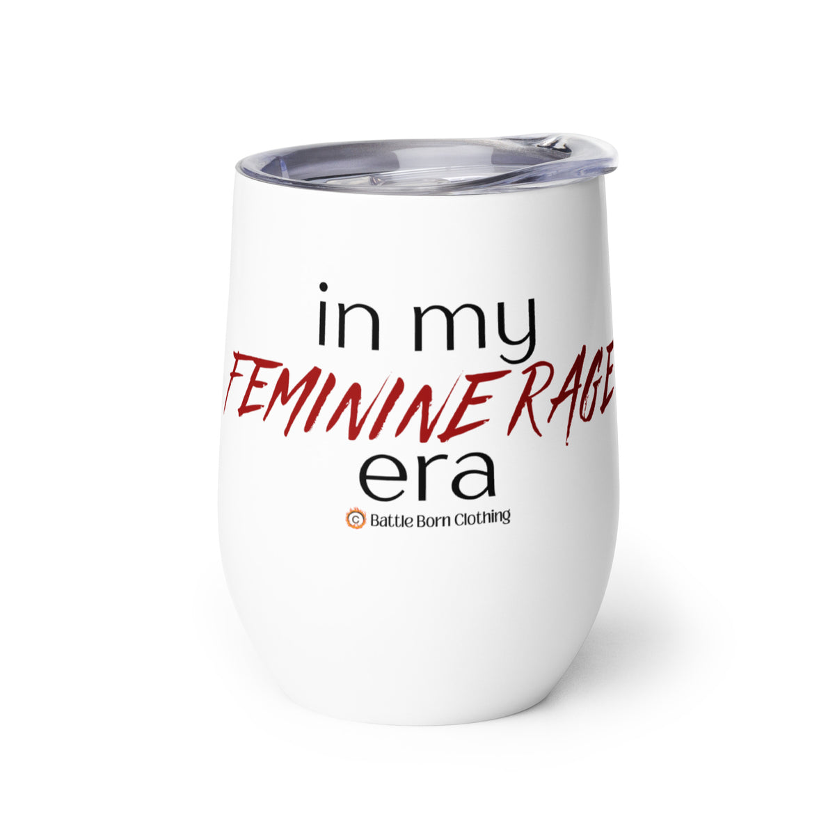 An insulated stemless wine glass with a lid for drinking wine in a tumbler. Cup is white in color with the words "in my feminine rage era". The words "feminine rage" are in red & a different font than the other words (other words are in black)