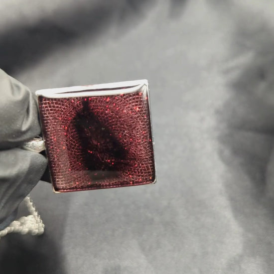Sparkly maroon colored resin pendant necklace in a square silver bezel.